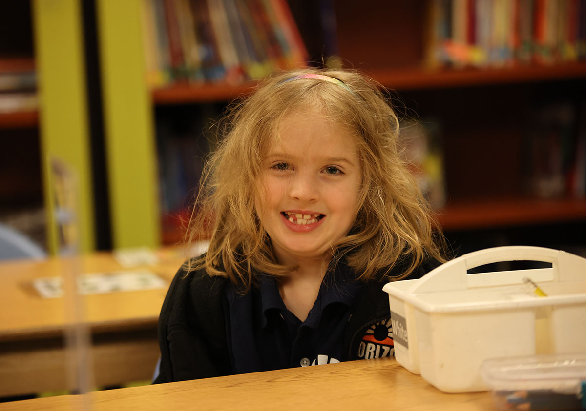 Elementary student smiling and posing together in a classroom.